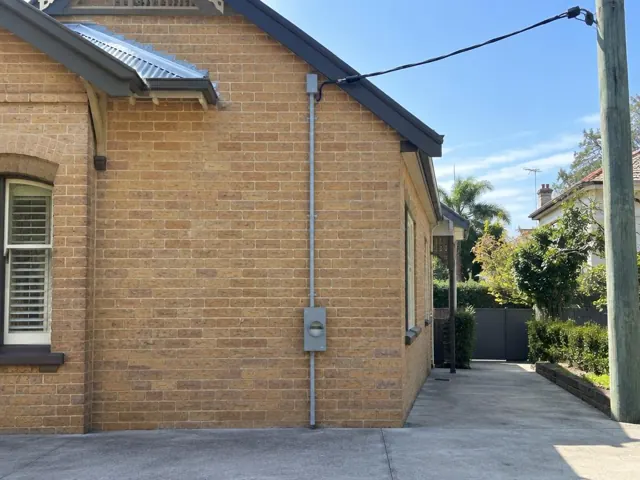 Brick house exterior with overhead service cable and attachment bracket on the wall in Edgecliff